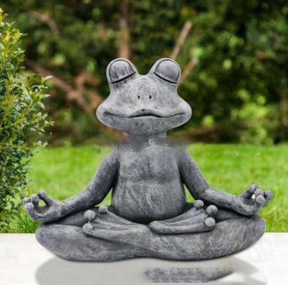 Stone frog statue in a meditative pose on a garden setting